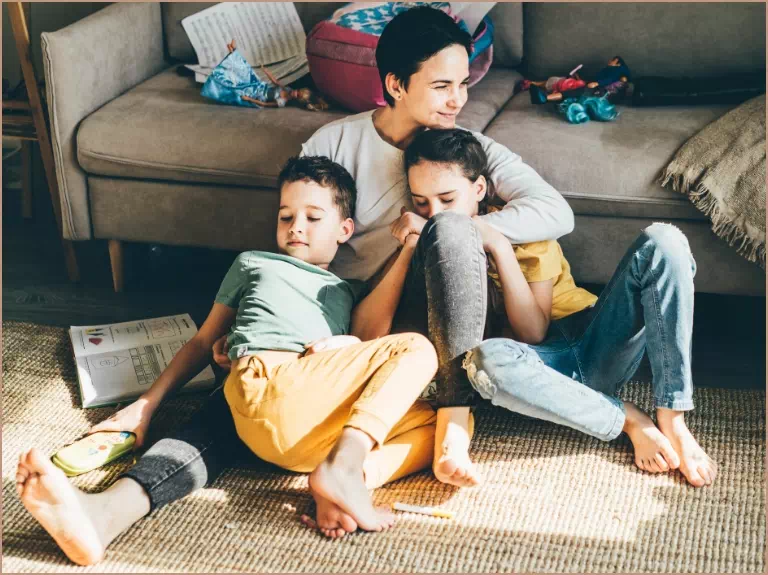 mama z dziećmi siedząca na dywanie